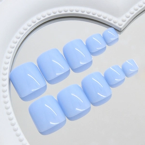 Set of glossy baby blue press-on toe nails arranged on a reflective mirror surface