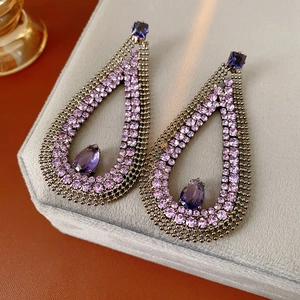 Macro shot of large teardrop earrings with purple crystals and dark metal mesh detail