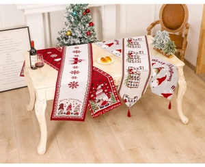 Detailed view of Christmas table runner with festive gnome embroidery and red tassels