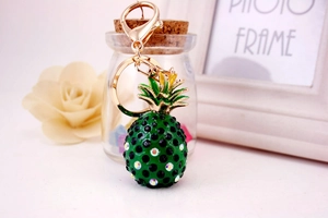 Close-up of green resin pineapple keychain with black rhinestones and golden clasp