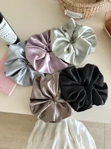 Detailed set of 5 large satin scrunchies in various colors with fashion label on table