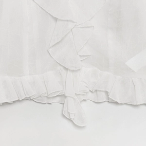 Close-up of white textured fabric showing ruffle details and hem drawstring on the shirt