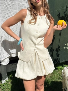 Détail d'un ensemble gilet en lin crème avec boutons et jupe bulle dans la nature