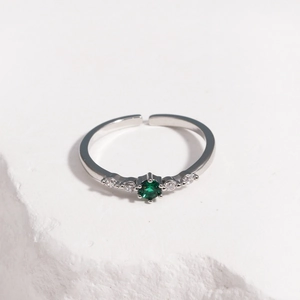 Detail of adjustable silver ring with faceted green zircon and clear side stones