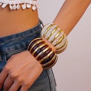 Close-up of chunky amber and white acrylic ribbed bangles on female model wrist