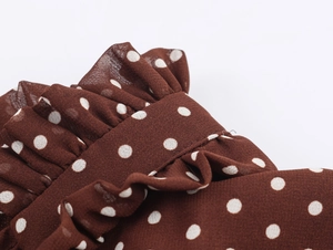 Dettaglio del tessuto in chiffon marrone a pois bianchi con strati di volant