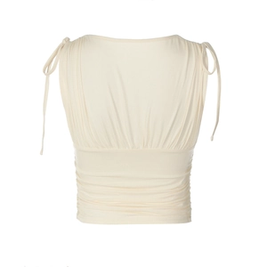 Dettaglio del crop top smanicato crema con texture increspata e lacci sulle spalle