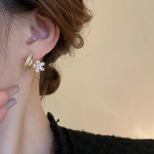 Elegant gold flower drop earrings with sparkling cubic zirconia on a female model