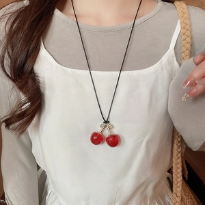 Detailed close-up of cherry pendant necklace with red spheres and metallic leaves