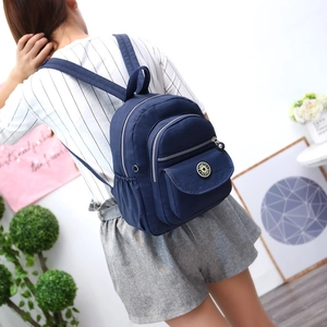 Blue nylon backpack for travel and school shown on a model in a bright room