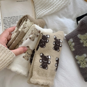 Detail of soft coral fleece socks with cute bear embroidery in cozy home setting