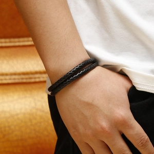 Detailed view of black double-wrap braided leather bracelet with magnetic clasp on wrist