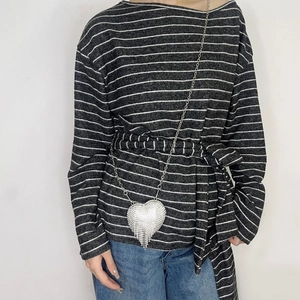 Detail of silver heart-shaped rhinestone bag with tassel fringe and metal chain strap