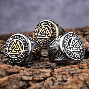 Macro shot of Viking Valknut rings in gold and silver steel on wooden texture