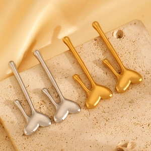 Close-up of geometric water drop earrings in gold and silver finish on stone surface