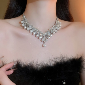 Gros plan du collier en V argenté orné de strass brillants et de perles élégantes