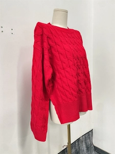 Detail view of red cable knit sweater featuring a side slit and textured knit pattern