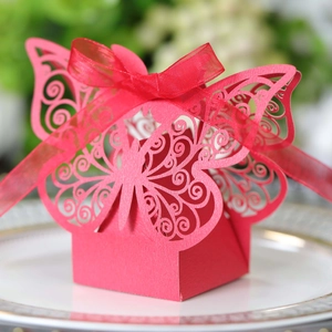 Macro view of red laser-cut butterfly candy box with silk ribbon for wedding decor