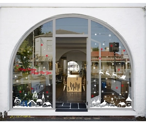 Detail showing white and red Christmas window decals on an arched glass door