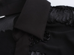 Detail of elegant black V-neckline featuring delicate floral embroidery on sheer mesh