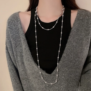 Détail d'un collier double épaisseur à perles argentées et pendentif perle sur un mannequin