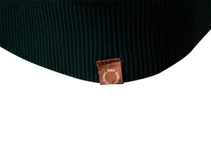 Macro detail of dark green ribbed knit sweater with brown embroidered logo patch