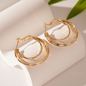 Macro view of gold layered geometric hoop earrings with textured diamond-cut finish