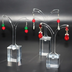 Acrylic jewelry stands displaying red gemstone earrings and beaded pendants on dark background