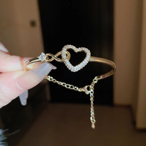 Detailed close-up of a gold-plated heart bracelet featuring white cubic zirconia stones