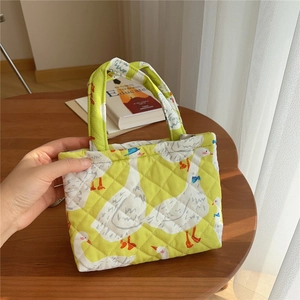 Detail of yellow quilted phone bag with white goose pattern and orange feet accents