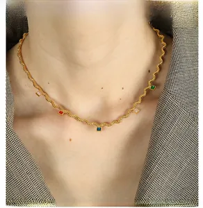 Detail view of wavy gold necklace with colorful square-cut zircon stones on a female model