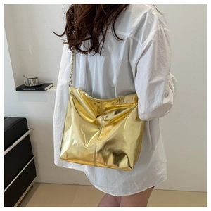 Rear view of model wearing a large golden reflective bucket bag with metal chain strap