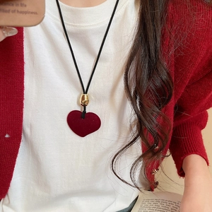 Detailed view of a red flocked heart pendant necklace with black cord on a model