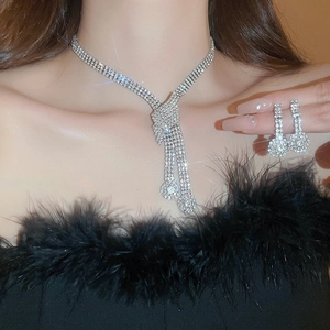 Close-up of sparkling rhinestone bow tassel necklace and earring set on model
