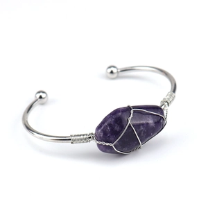 Close-up of handmade silver wire wrapped natural purple crystal on open cuff bracelet