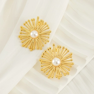 Detail view of gold sunburst earrings with center pearls on elegant fabric backdrop