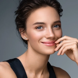 Close-up of sparkling silver bow earrings with moissanite studs worn on model's ear