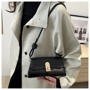 Chic black faux leather underarm bag with gold metal clasp and knotted shoulder strap