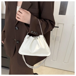 Close-up of soft white pleated cloud bag with silver chain strap on a model shoulder