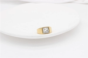 Close-up of gold plated wide band ring featuring a large square transparent gemstone