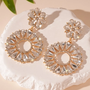 Detailed close-up of crystal flower hoop earrings with pear-shaped rhinestones on stone