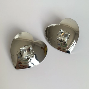 Macro shot of silver heart earrings with a square-cut sparkling crystal center