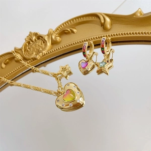 Macro view of gold-plated heart and star earrings with colorful gradient rhinestones