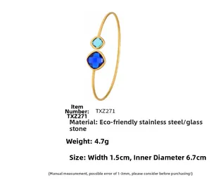 Detail of stainless steel gold open bangle with square cut blue glass stones
