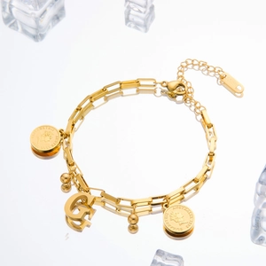 Macro view of gold stainless steel chain bracelet with Elizabeth coin and letter G charm