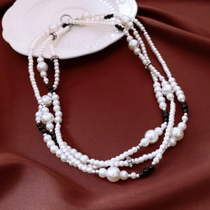 Détail d'un collier de perles multicouches avec perles nacrées blanches noires et argentées