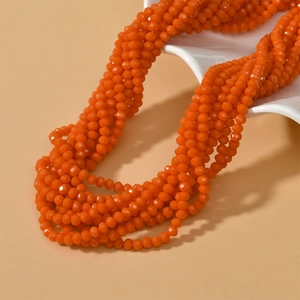 Orange faceted glass rondelle bead necklace displayed on a white wavy ceramic jewelry tray
