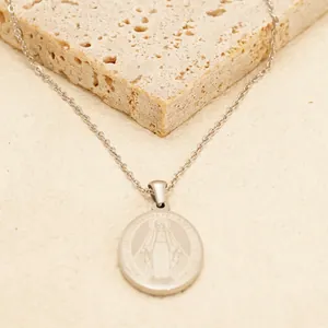 Vintage stainless steel Virgin Mary portrait cross necklace on elegant stone background