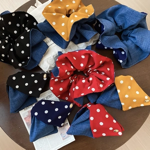 Close-up of polka dot and denim scrunchies with engraved love metal charms on a table
