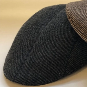 Detail shot of twill wool fabric and precision stitching on dark grey and tan flat caps